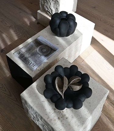 Artistieke zwarte keramische schalen tentoongesteld op minimalistische stenen tafels met natuurlijke texturen