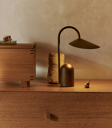 Elegante tafellamp met een sculpturaal design op een houten dressoir in zacht omgevingslicht