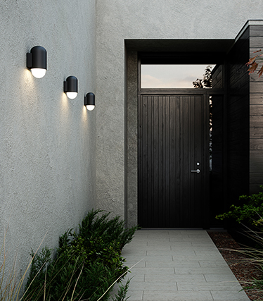 Moderne wandlampen voor buiten die de ingang van een moderne woning bij schemer verlichten