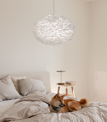 Fluffy hanglamp die een warme en ontspannen sfeer creëert in een moderne slaapkamer met een hond die op het bed rust