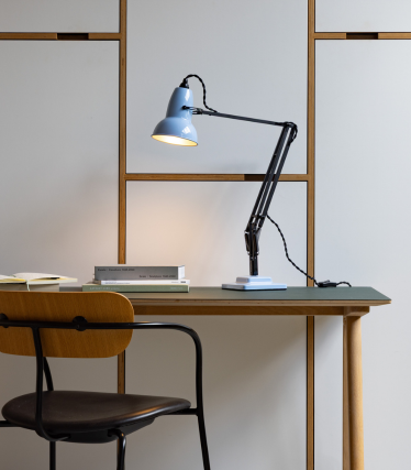 Lichtblauwe Anglepoise bureaulamp op een houten tafel met stoel