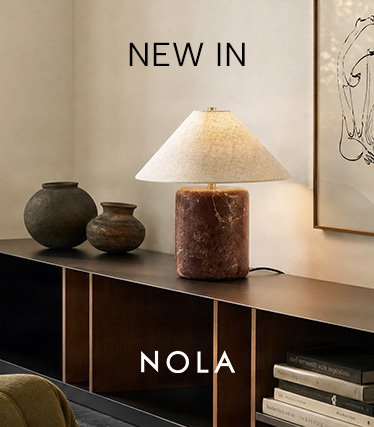 Nola tafellamp met roodbruine marmeren voet en conische linnen kap op een donker dressoir. Tekst: ‘Nieuw – Nola’.